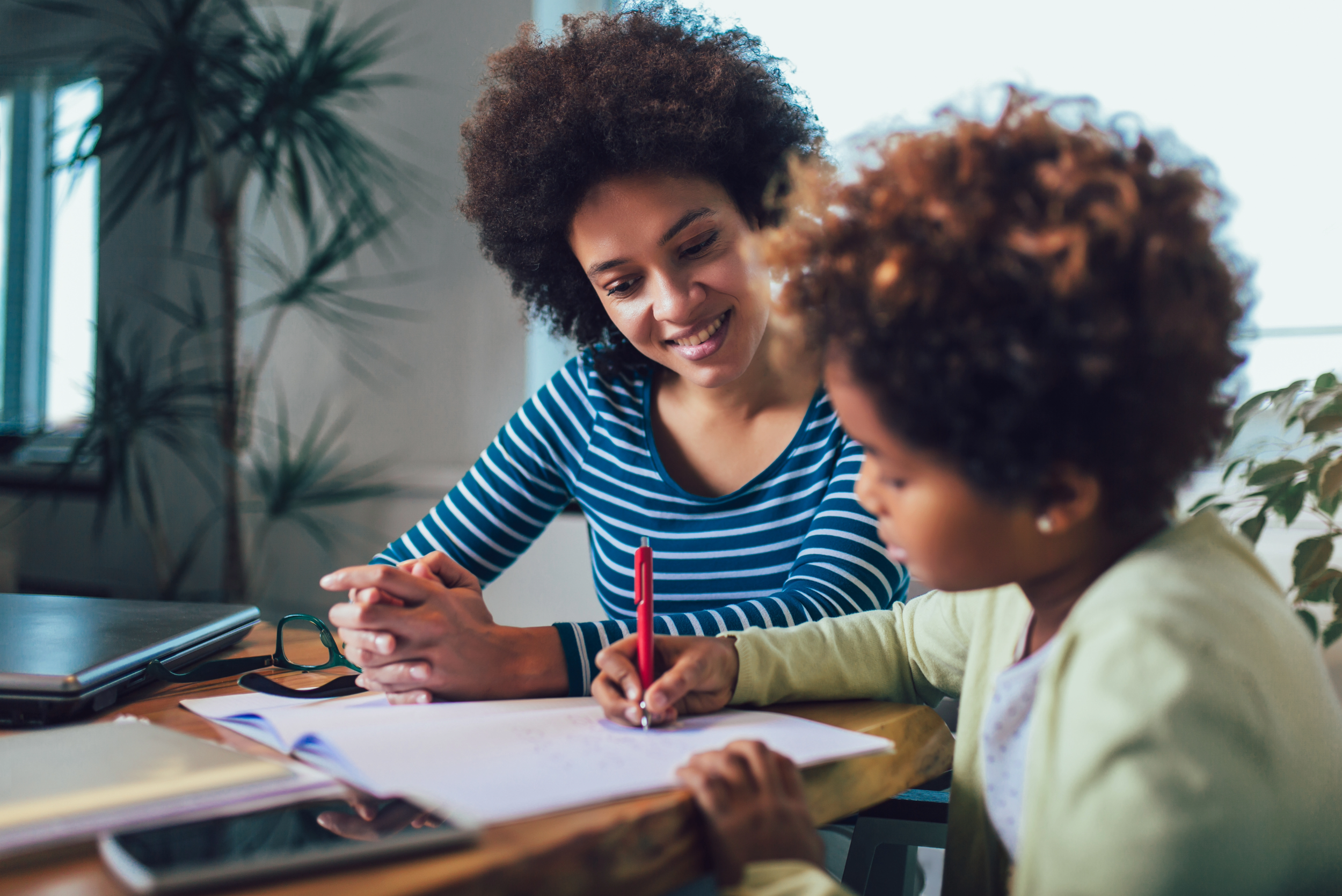 Women sitting at a table with a child doing schoolwork